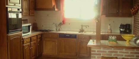 A kitchen with wooden cabinets, a microwave, a sink, and a brick wall.