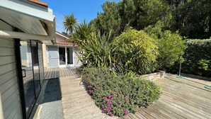 A wooden deck with a garden area featuring various plants and flowers. - Near Soulac/mer, house 3 bedrooms, sleeps 6, heated indoor pool (Grayan-et-l'Hôpital)