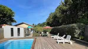 A wooden deck with a swimming pool, white lounge chairs, and a small building with windows. - Near Soulac/mer, house 3 bedrooms, sleeps 6, heated indoor pool (Grayan-et-l'Hôpital)