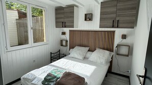 A bedroom with a bed, wooden headboard, bedside tables, and a window. - Near Soulac/mer, house 3 bedrooms, sleeps 6, heated indoor pool (Grayan-et-l'Hôpital)