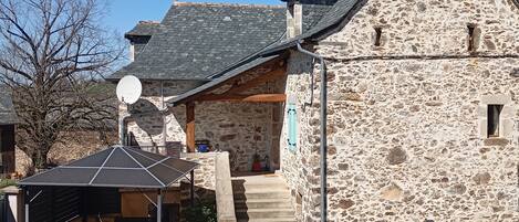 A stone building with a sloped roof, a satellite dish, and a staircase leading to an upper level.
