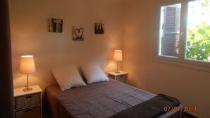 Ein Schlafzimmer mit einem Bett, zwei Nachttischen, einem Fenster mit Rollläden und Wandbildern.