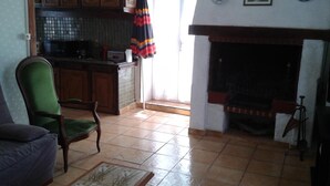 Una sala de estar con un sillón verde, una mesa de centro con motivos y una chimenea.