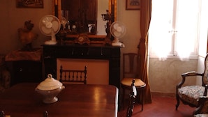 Una habitación con chimenea, dos ventiladores de pared, una mesa de madera, una silla y un espejo grande.