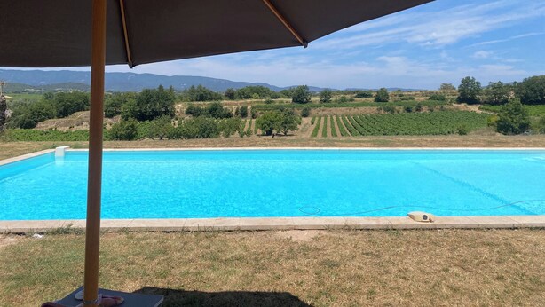 Una piscina con vistas a viñedos y montañas al fondo.