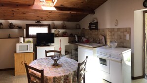 Une cuisine compacte avec un plafond en bois, une table à manger avec des chaises, un four à micro-ondes, une cuisinière et un évier.