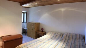 Une chambre à coucher avec un lit, une armoire en bois, un bureau et une chaise.