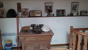 Un meuble en bois contenant une radio, un poêle d’époque et une casserole blanche.