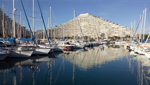A marina with multiple boats docked, a large cruise ship in the background, and a clear blue sky. - AIR-CONDITIONED, SINGLE-STOREY VILLA, SEA AND CORSICAN VIEWS LARGE GARDEN, DOGS ALLOWED (Villeneuve-Loubet)
