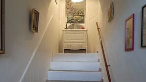 Una escalera con escalones blancos que conduce a un rellano con una chimenea blanca y un cuadro encima.