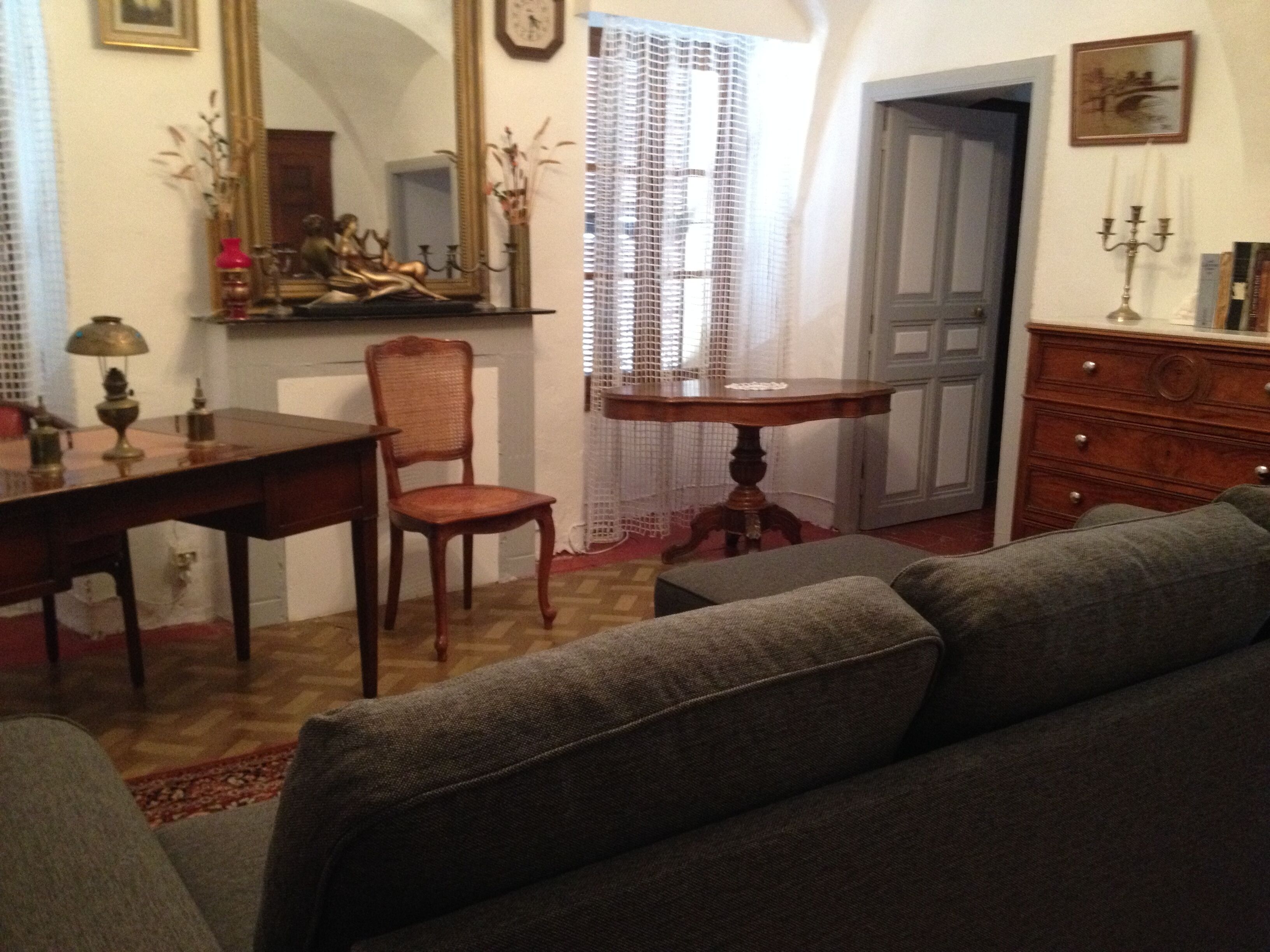 Un salon comprenant un canapé, une chaise en bois, une table à manger, un miroir et une commode.