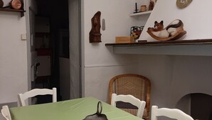 Un comedor con una mesa verde, sillas blancas, un reloj y una estantería con forma de gato.