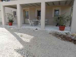 A covered outdoor seating area with tables and chairs, surrounded by potted plants and a gravel ground. - Dordogne Valley, Black Périgord, Independent cottage on the edge of the forest. (PEYRILLAC ET MILLAC)