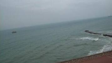 A coastal view with a stone wall and a boat in the distance.
