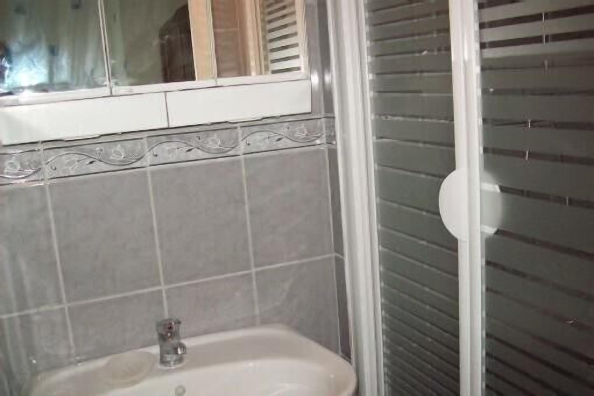 Een badkamer met een wastafel, een spiegel en een douchecabine.