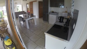 A modern kitchen with a dining area, a washing machine, and a coffee maker. - Villa Marga: pretty new Creole villa (Capesterre - Belle - Eau)