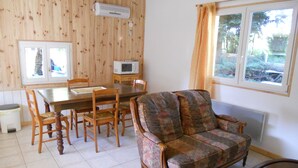 Een eetgedeelte met een houten tafel en stoelen, een gestreept sofa en een raam met gordijnen.