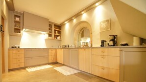 Une cuisine moderne avec des meubles en bois, un four encastré et une machine à café.