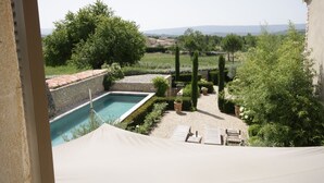 Un espace piscine agrémenté d’un mur en pierre, d’une pergola et offrant une vue sur la campagne.
