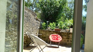 A patio with a stone wall, a red chair, and a white folding chair. - Chez Mathilde in Rarécourt (Rarécourt)