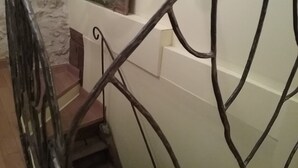 A staircase with a metal railing, a stone wall, and a painting on the wall. - Chez Mathilde in Rarécourt (Rarécourt)