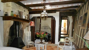 A room with a fireplace, a chandelier, a dining table, and a flower vase. - Chez Mathilde in Rarécourt (Rarécourt)