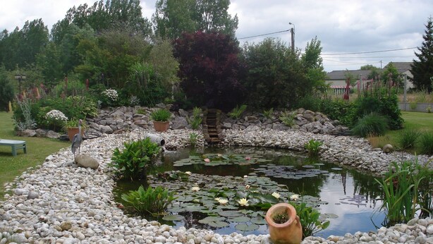 A pond surrounded by white pebbles, with a bird standing on the edge. - very beautiful house of 140m2 located in a private property (Quend)