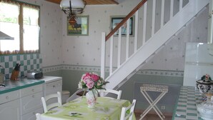 A kitchen with a dining table set for two, a staircase, and a window with curtains. - very beautiful house of 140m2 located in a private property (Quend)