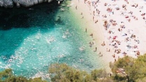 A coastal beach with rocky cliffs and clear turquoise water.