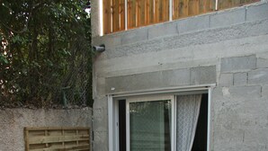 A small patio area with a table and two chairs, a wooden fence, and a sliding glass door.