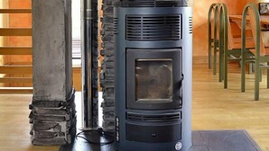 Une cheminée en pierre au design moderne, dotée d’une hotte et d’une porte en verre.