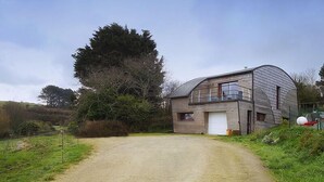 Une maison moderne avec un toit incurvé et un garage.