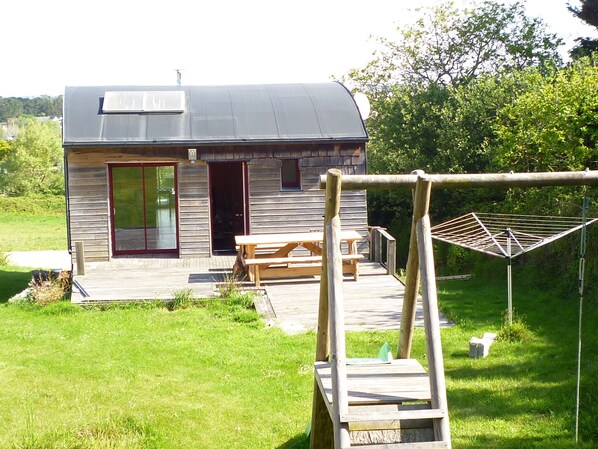 A small wooden cabin with a sloped roof, a patio with a table and benches, and a clothesline in the yard. - Seasonal rental by the sea in Plouarzel (Plouarzel)