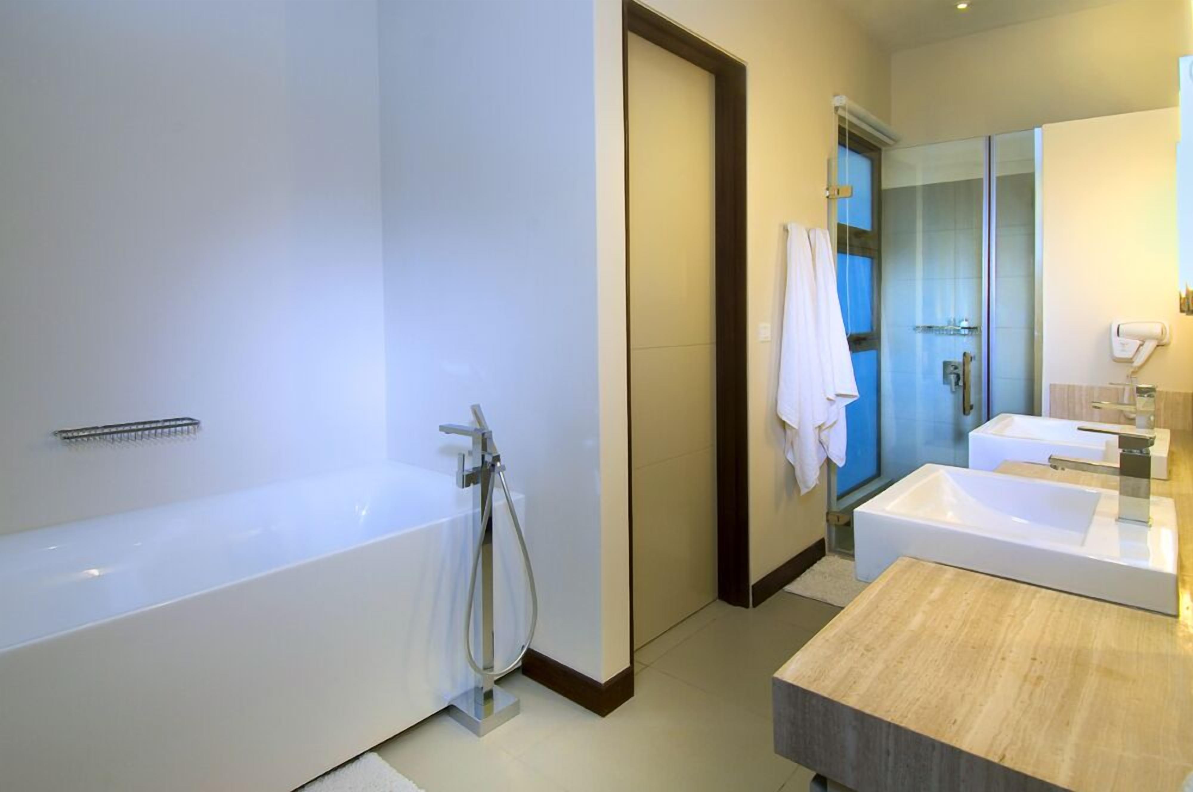 Une salle de bain moderne avec une baignoire, un grand miroir et un espace lavabo séparé.
