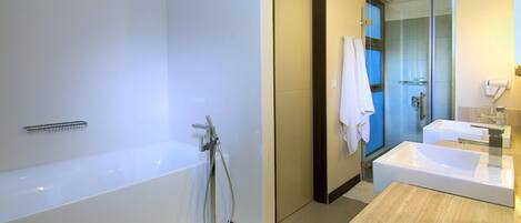 Une salle de bain moderne avec une baignoire, un grand miroir et un espace lavabo séparé.