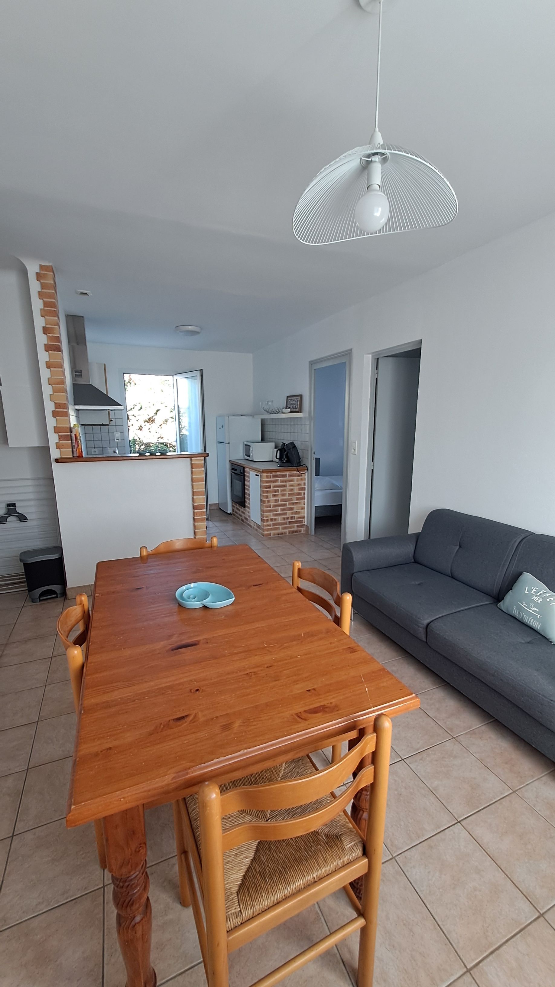 A modern living space with a dining area, kitchen, and a sofa.