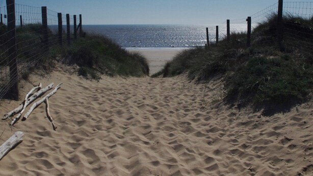 A sandy beach path leading to the ocean, flanked by wooden posts and wire fencing. - Terraced house, independent, 100 m from the beach of Rémigeasse (Dolus-D'oléron)