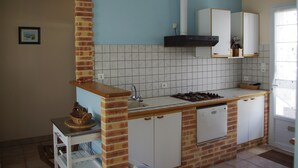 A kitchen with a brick column, white cabinets, a gas stove, and a white dishwasher. - Terraced house, independent, 100 m from the beach of Rémigeasse (Dolus-D'oléron)
