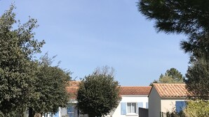 A pathway leading to a building with a red-tiled roof, surrounded by trees and a grassy area. - Terraced house, independent, 100 m from the beach of Rémigeasse (Dolus-D'oléron)