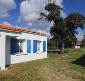Un bâtiment blanc avec des volets bleus et un toit recouvert de tuiles.