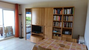 Een kamer met een houten boekenkast, een televisie en een tafel met een bloemendecoratie.