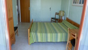 Een slaapkamer met een bed, een stoel, een bureau en een kledingkast.