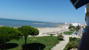 Uitzicht op de kust vanaf een balkon, met een strand en heldere lucht.
