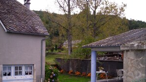 A house with a garage, a covered porch, and a garden with flowers and a fence. - Colorful house in a green hamlet (Forgès)