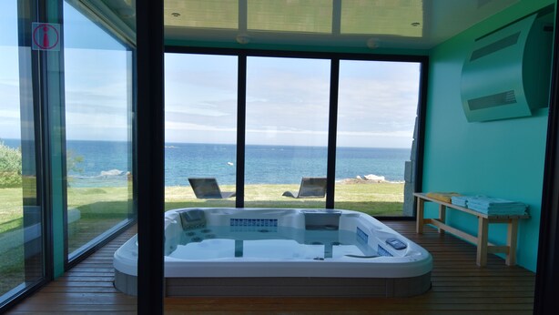 Una habitación moderna con un amplio ventanal que da a un balcón con vistas al mar.