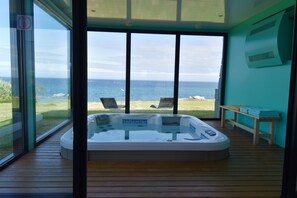 A modern room with a large glass door leading to a balcony overlooking the sea.