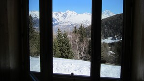 Ein Zimmer mit großem Fenster und Blick auf eine verschneite Berglandschaft.