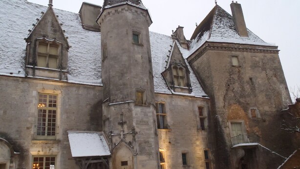A historic building with a central tower, multiple windows, and a snow-covered roof.