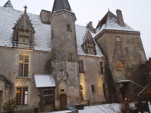 Un edificio histórico con una torre central, varias ventanas y un tejado cubierto de nieve.