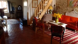 A cozy living room with a wooden staircase, a red sofa, a wooden coffee table, and a vase of yellow flowers.